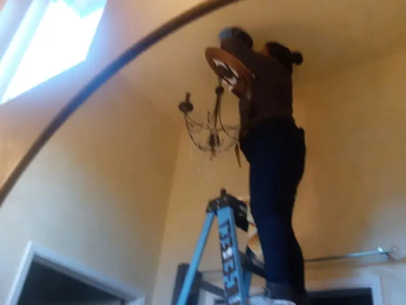 Electrician installing a chandelier in a Lenoir residence